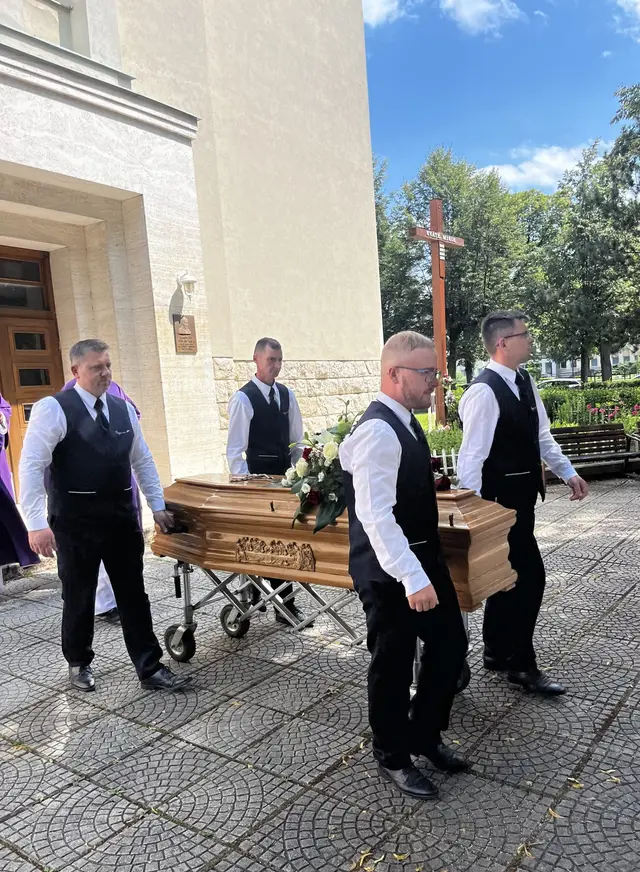 Nosiči Paciga nesú rakvu s kvetmi pred kostolom